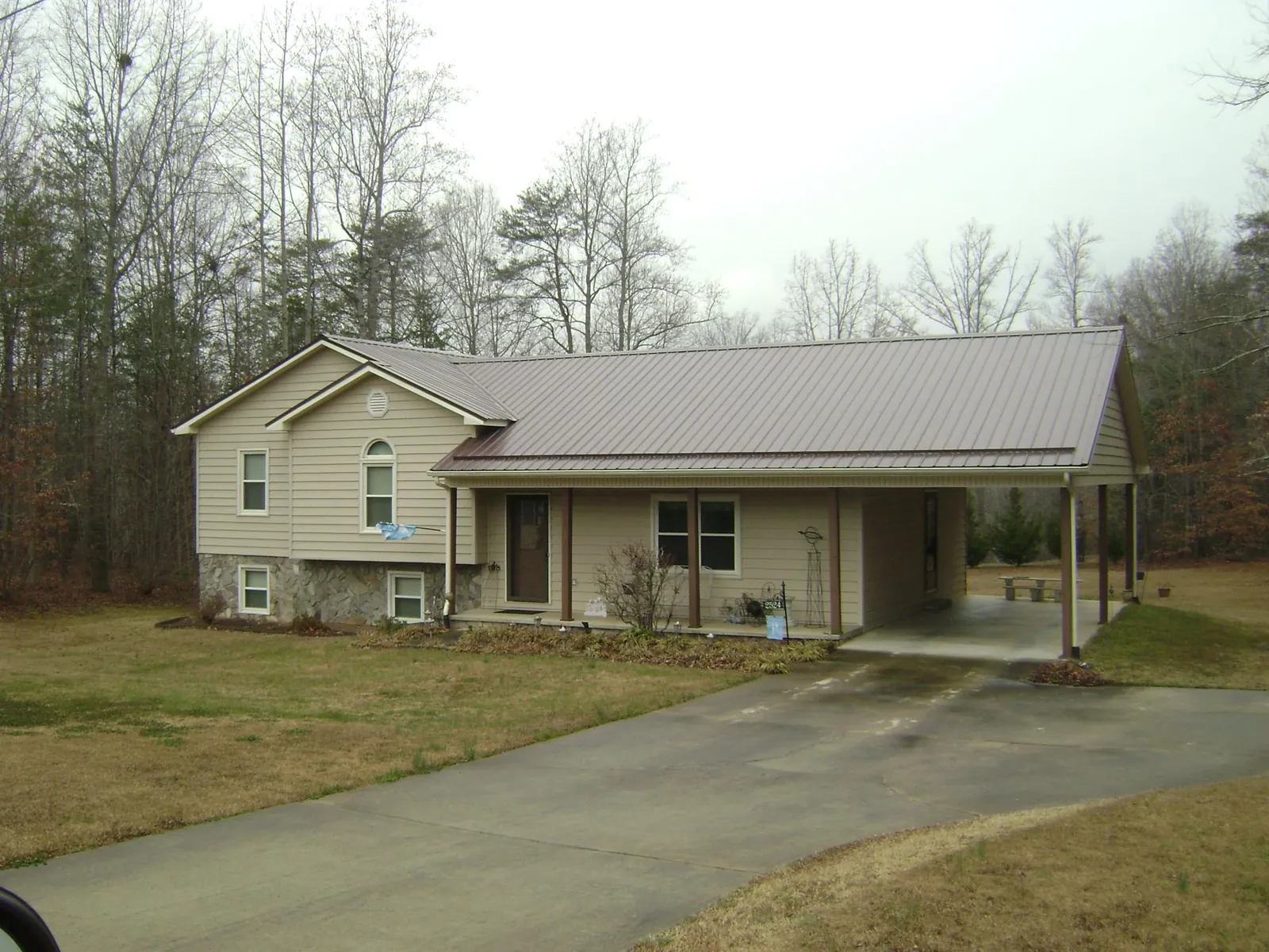Brown metal roof on a tan split level home with an attached carport in Maple Valley