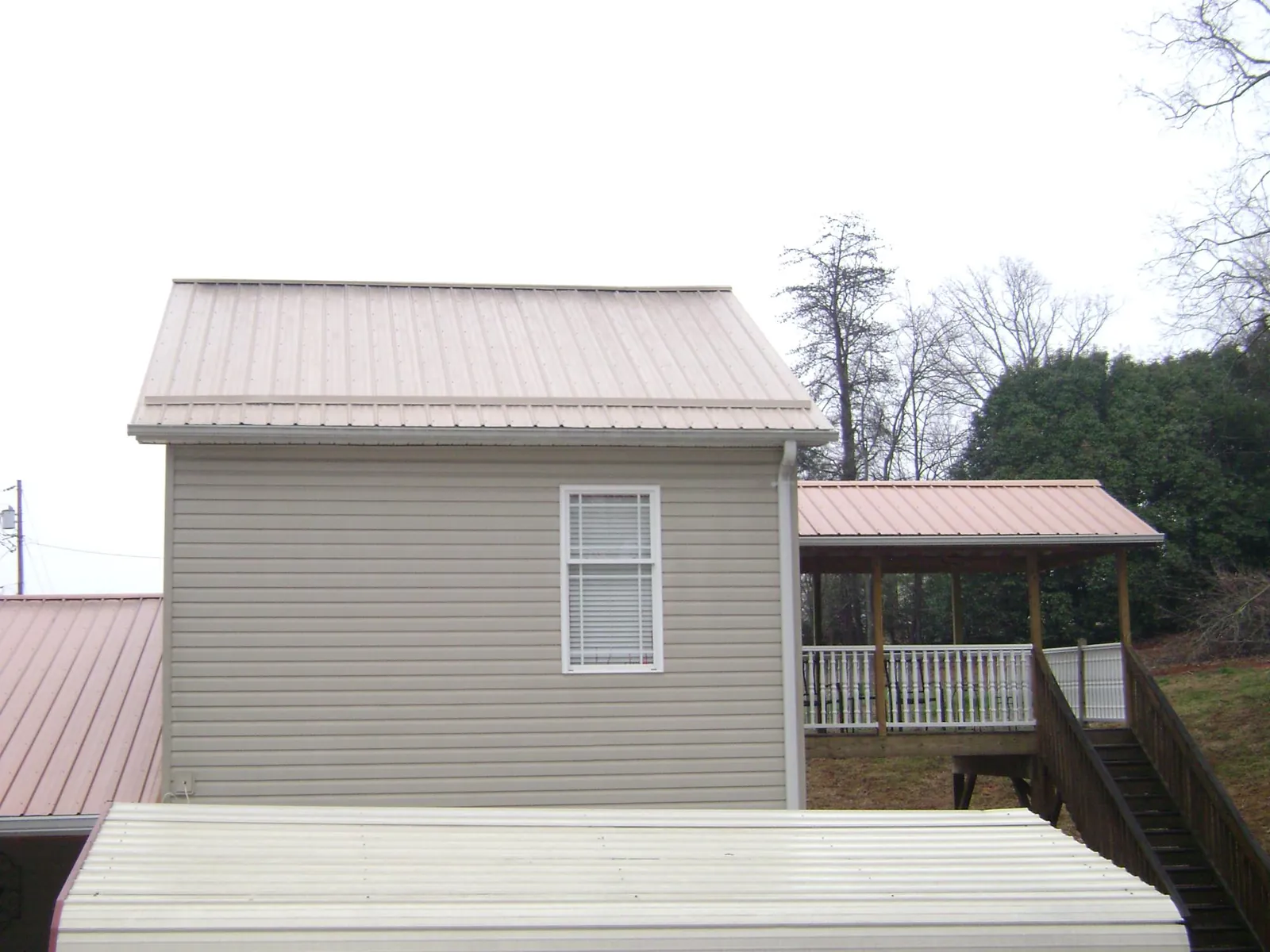 Tan metal roofs on a two story addition and attached porch, from a Roof Replacement job in Maple Valley