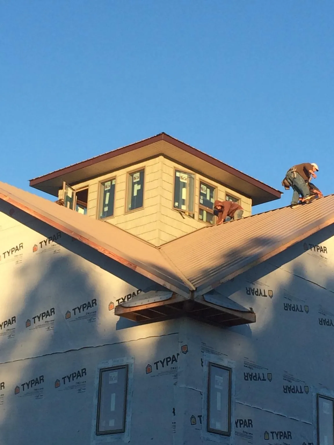Roofers working around a rooftop cupola on a new metal roof at sunset — Roof Waterproofing in Maple Valley by Roofing Brothers